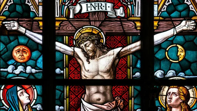 Glas-in-loodraam met een afbeelding van Jezus aan het kruis, met touwen om Zijn armen en spijkers door Zijn handen. Hoogstwaarschijnlijk werd Hij – zoals iedere gekruisigde – door de Romeinen volledig naakt aan het kruis vastgemaakt, als ultieme vernedering.