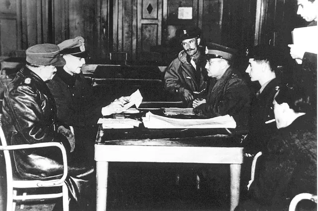 1945-05-05 00:00:00 Hotel De Wereld, Wageningen, 5 mei 1945. Onderhandelingen over de capitulatievoorwaarden. Links: Duitse tolk, generaal Reichelt. Rechts: brigadier George Kitching (boven), luitenant-generaal Charles Foulkes (midden) en uiterst rechts ZKH Prins Bernhard. ANP.