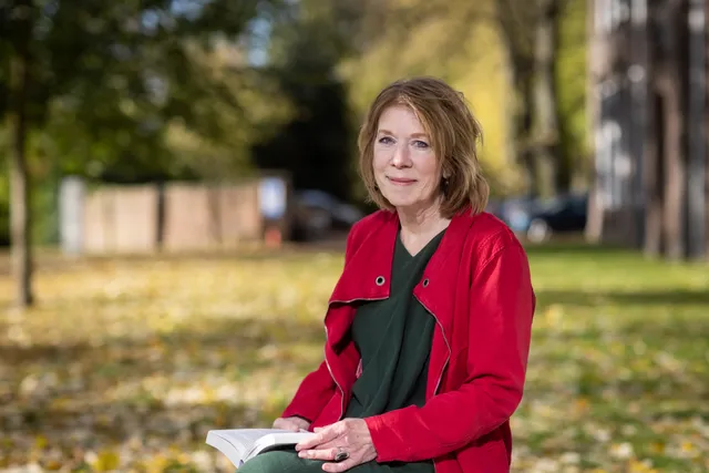 Petra de Joode met een boek in de natuur.